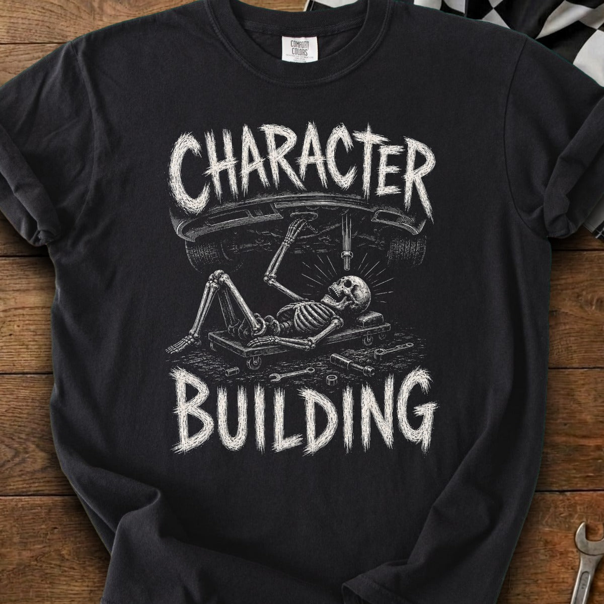 Black t-shirt with skeleton working on a car, text "CHARACTER BUILDING"