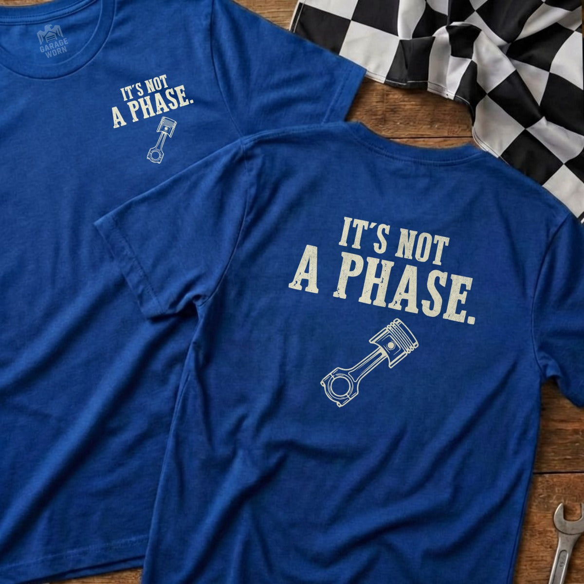 Two blue t-shirts with white text "IT'S NOT A PHASE." and a piston graphic.