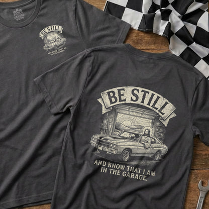 T-shirt with "Be Still and Know That I Am In The Garage" text and graphic.