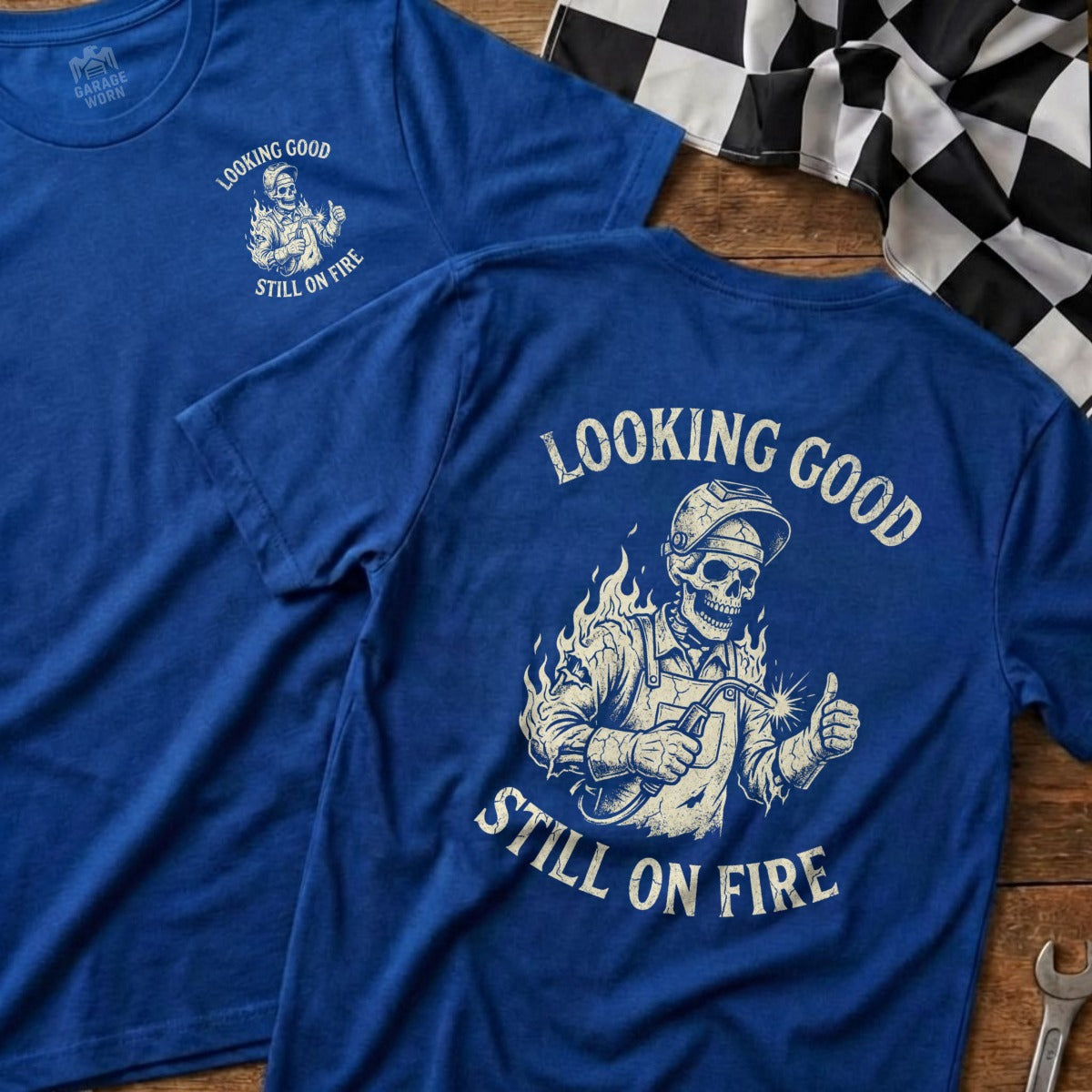 Blue t-shirt with skeleton welder and text "Looking Good Still On Fire".