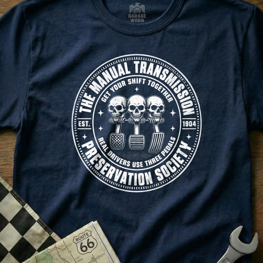 Navy t-shirt with "Manual Transmission Preservation Society" circular graphic and three skulls.