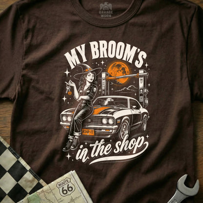 Witch in witch hat leans on muscle car, text "My Broom's in the shop".