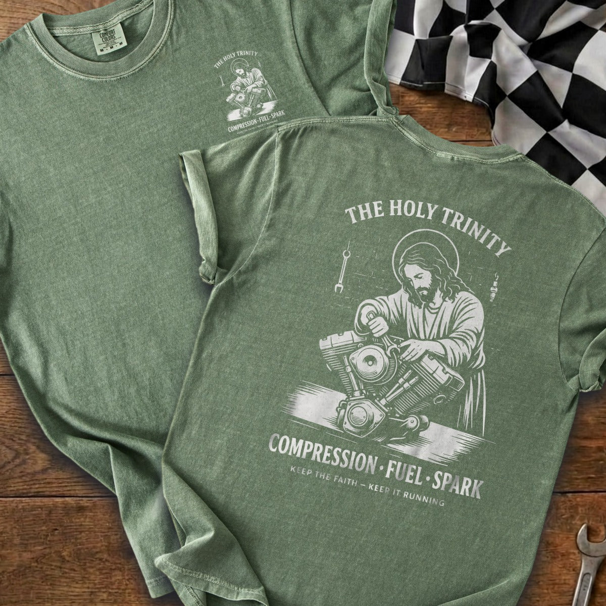 Green t-shirt with graphic featuring Jesus working on a motorcycle engine.