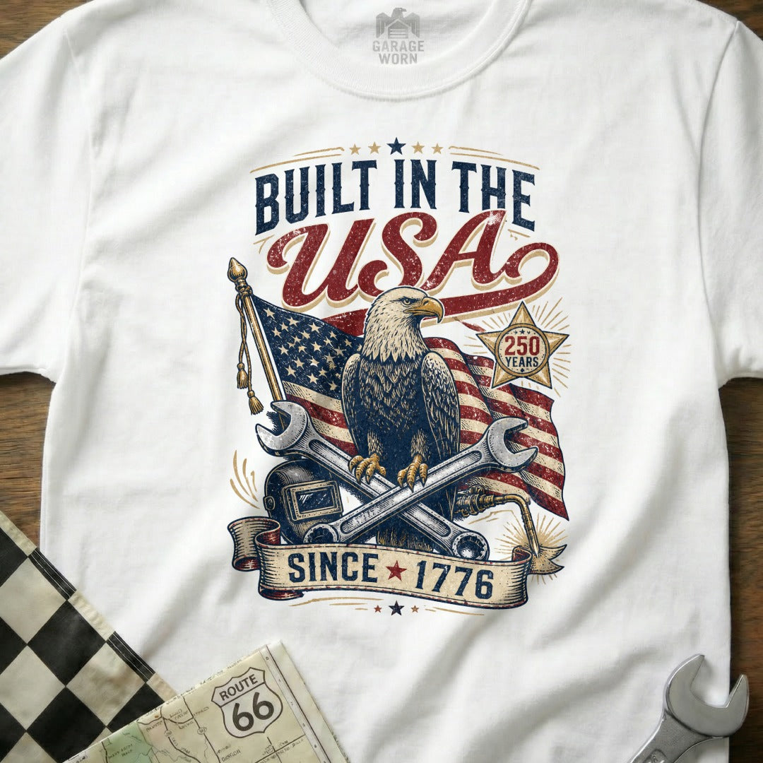 White t-shirt with eagle, US flag, tools, and text "Built in the USA Since 1776".