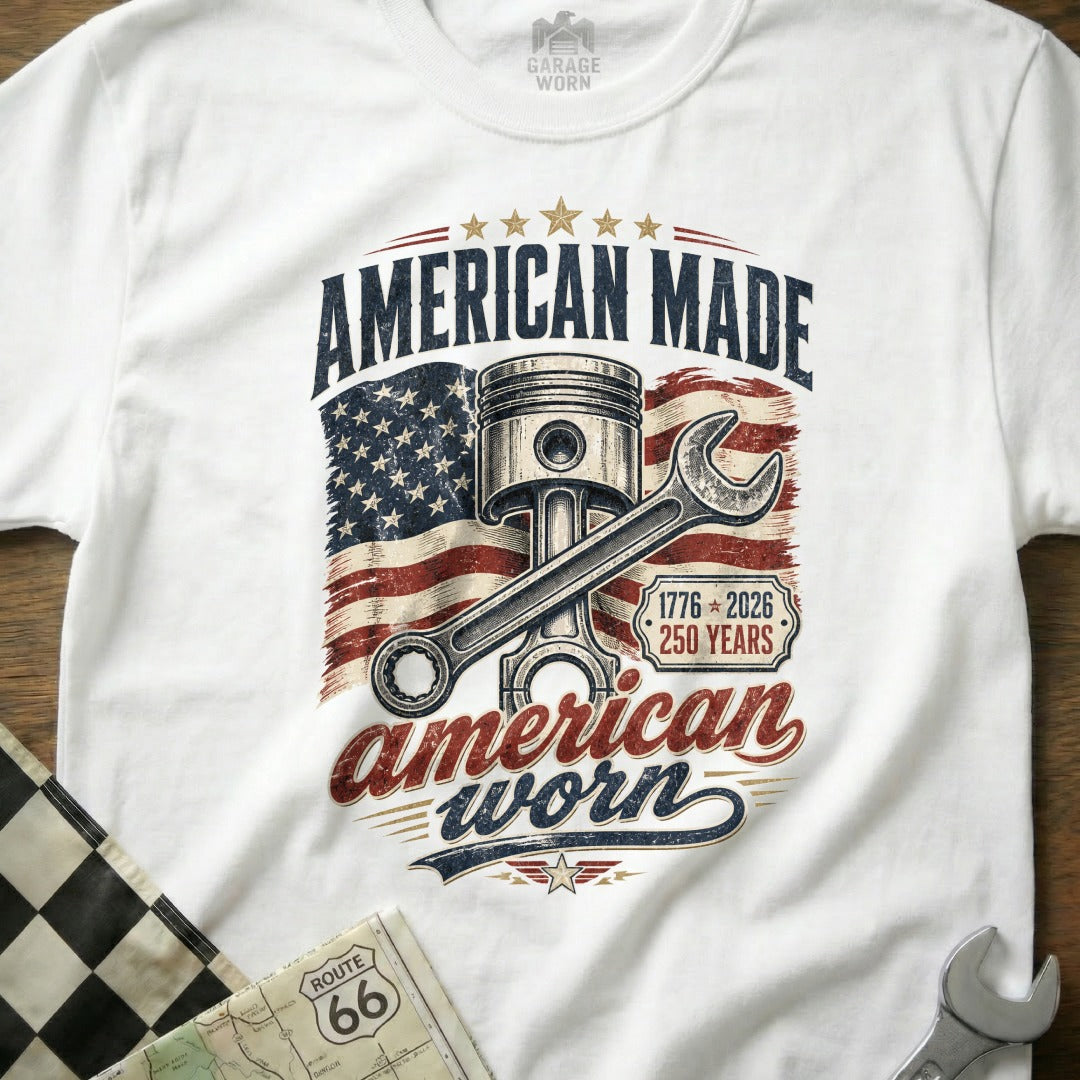 White t-shirt with American flag, piston, wrench, and "American Made American Worn" text.