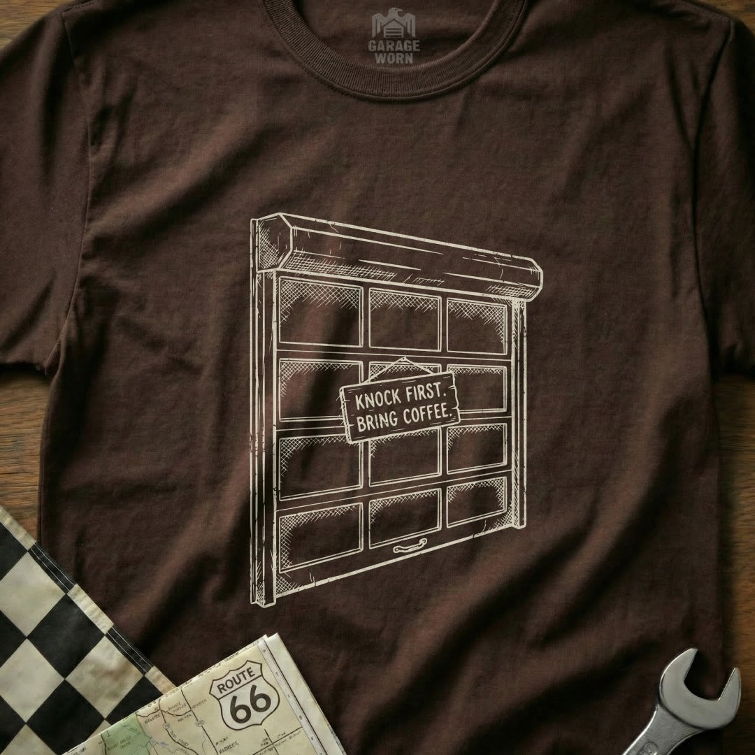 Brown t-shirt with sketch of a garage door that says "Knock first. Bring coffee."
