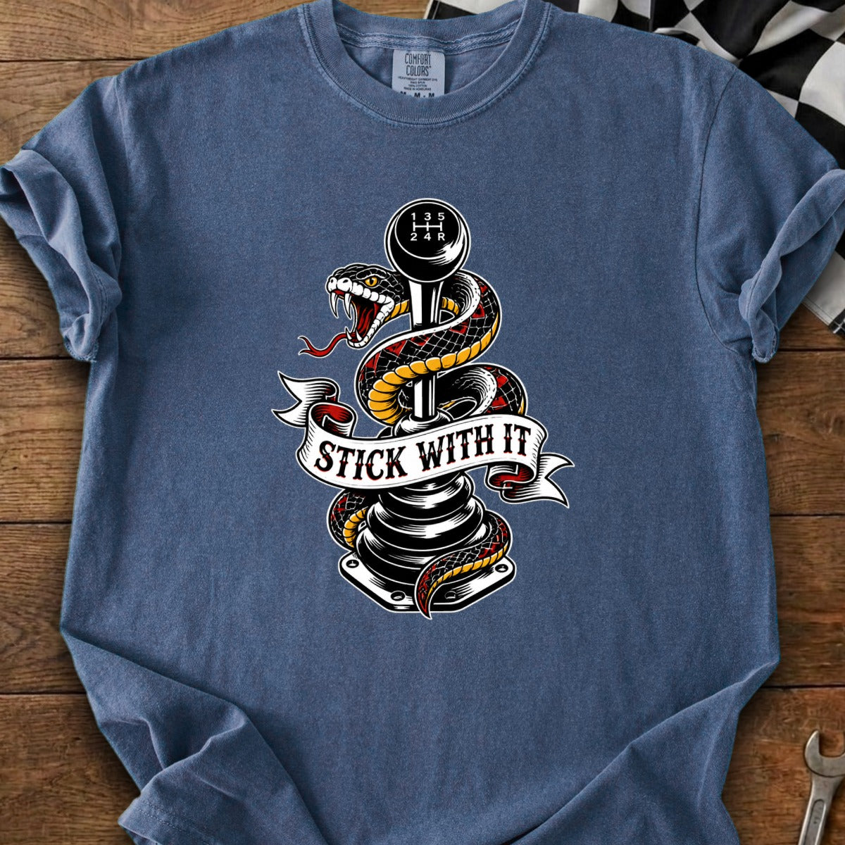 T-shirt with snake wrapped around a manual transmission shift knob, banner reads "Stick With It".