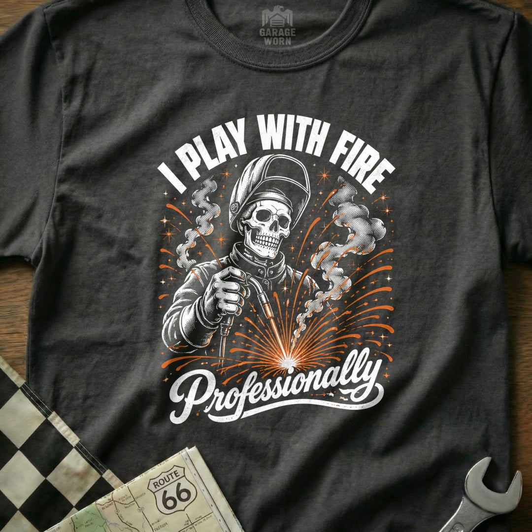 Dark t-shirt with graphic of a skull welder saying "I Play With Fire Professionally".
