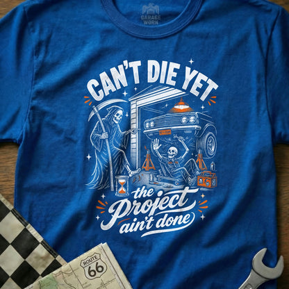 Grim Reaper and skeleton work on car in garage; text reads "Can't Die Yet The Project Ain't Done."
