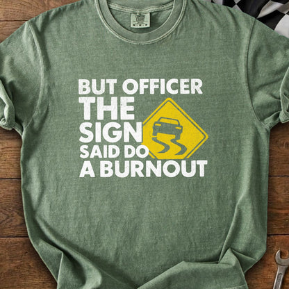 Green t-shirt with text "BUT OFFICER THE SIGN SAID DO A BURNOUT" and a slippery road sign.