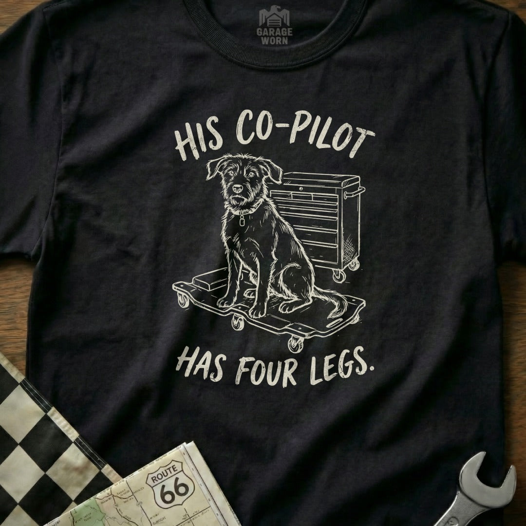 Black t-shirt with white graphic of dog on toolbox, text reads "His co-pilot has four legs."