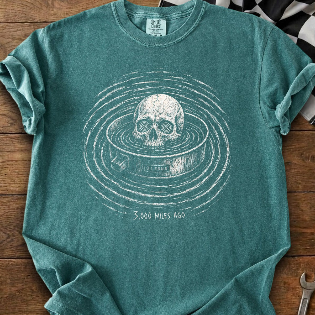 Skull in oil drain with concentric circles and text "3,000 MILES AGO".