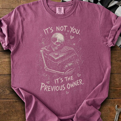 Skeleton holding engine on maroon t-shirt with text "It's not you. It's the previous owner."