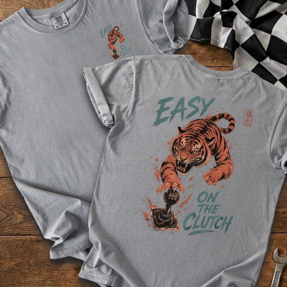 Grey t-shirt with graphic of tiger clutching gear stick, reading "EASY ON THE CLUTCH".