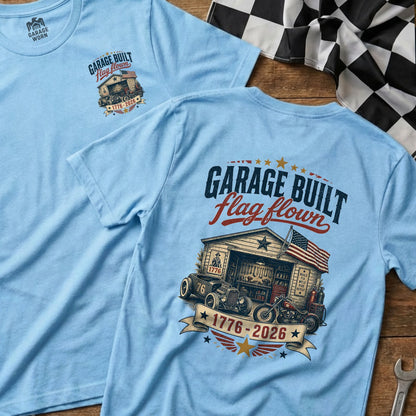 Light blue t-shirt with Garage Built Flag Flown graphic featuring a garage, hot rod, and motorcycle.
