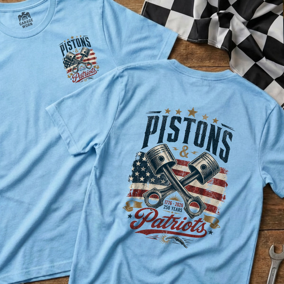 Light blue t-shirt with "Pistons & Patriots" graphic featuring crossed pistons and US flag.