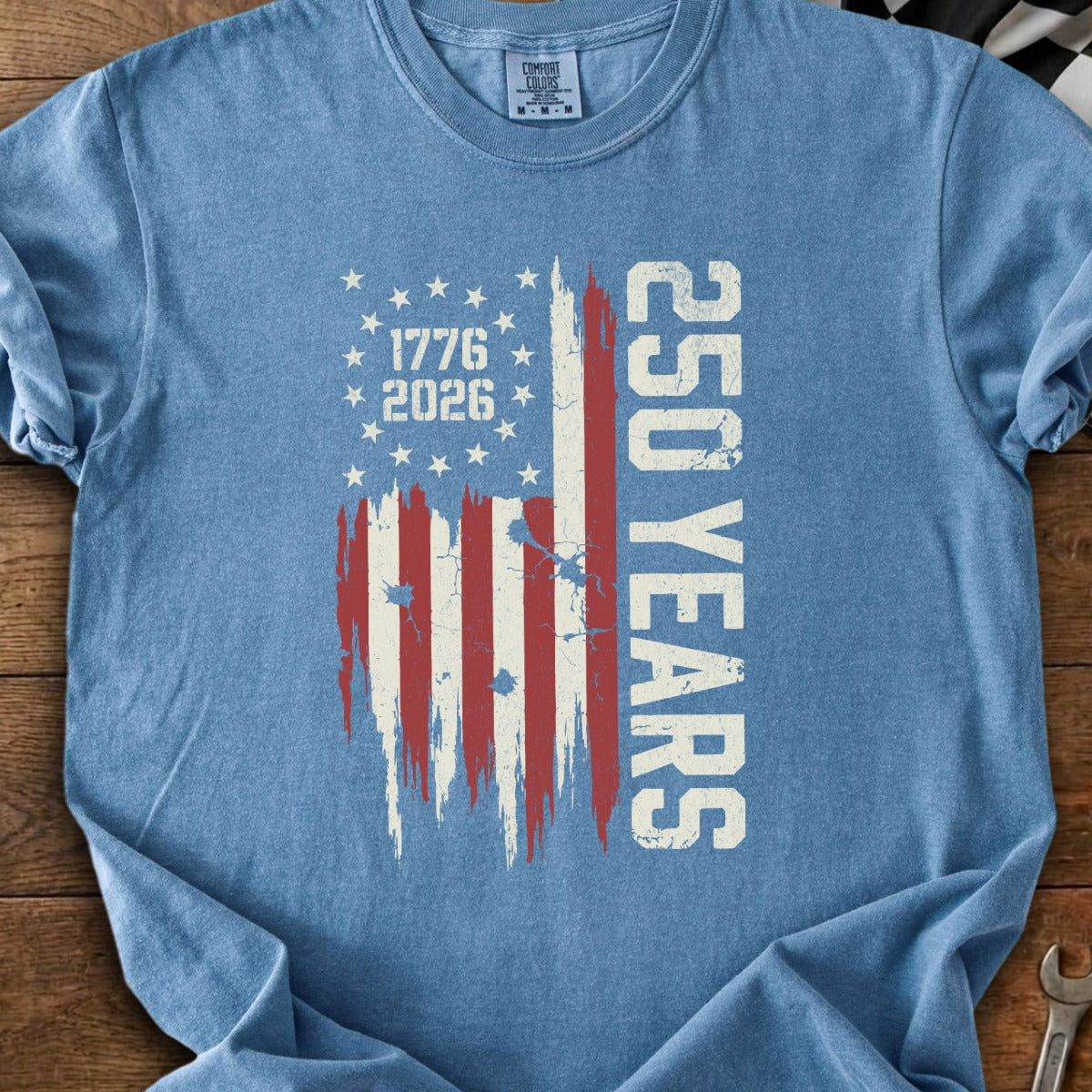 Blue t-shirt with distressed American flag graphic and text stating "1776 2026 250 YEARS".