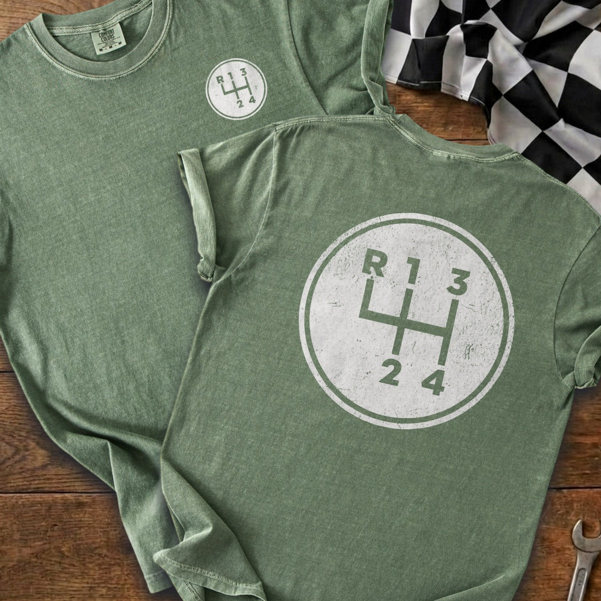 Green t-shirts with a white graphic of a manual transmission gear shift pattern.