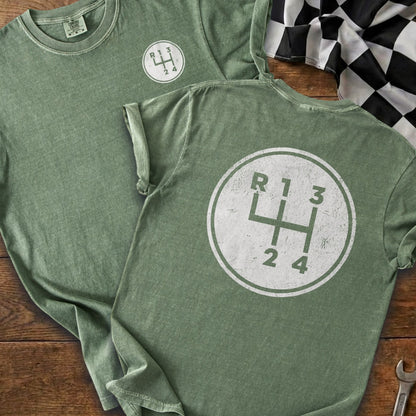 Green t-shirts with a white graphic of a manual transmission gear shift pattern.