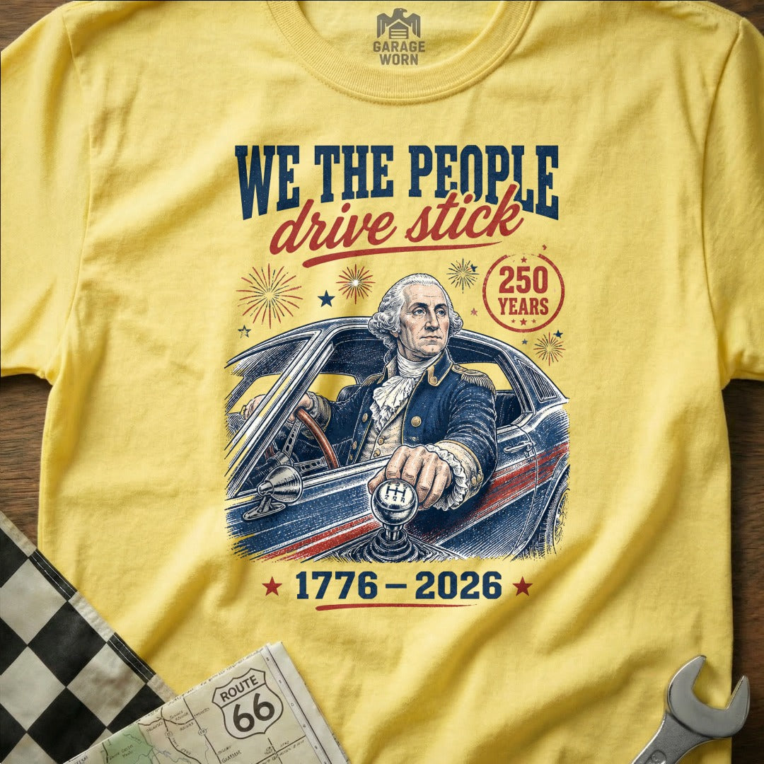 Yellow t-shirt with George Washington driving a car, "We the People drive stick" text.