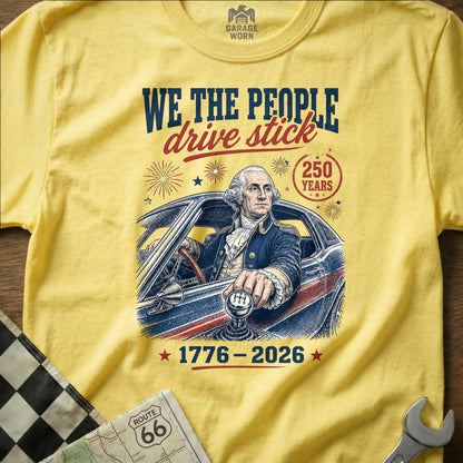 Yellow t-shirt with George Washington driving a car, "We the People drive stick" text.