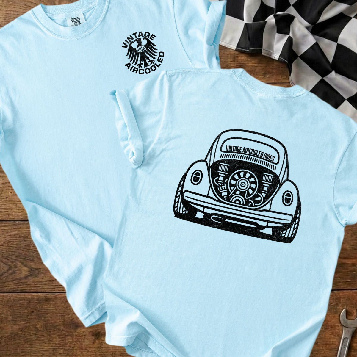 Light blue t-shirt with a black graphic of a Volkswagen Beetle's engine and the text "Vintage Aircooled Rides".