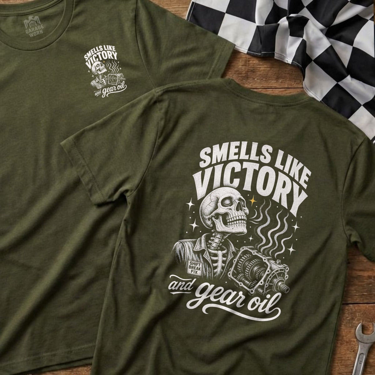 Olive green t-shirt with skeleton, transmission, and text "Smells Like Victory and Gear Oil."