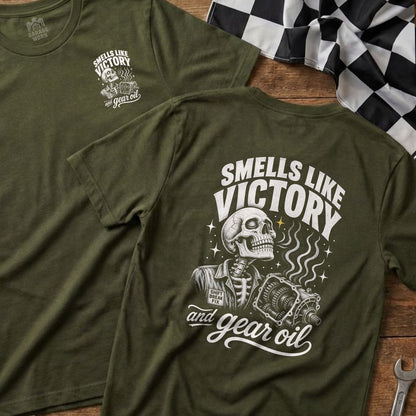 Olive green t-shirt with skeleton, transmission, and text "Smells Like Victory and Gear Oil."