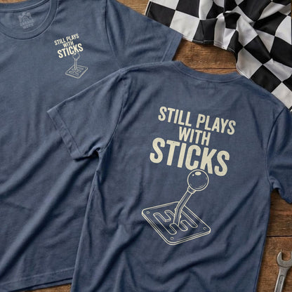 Navy t-shirt with "Still Plays With Sticks" and a manual transmission stick shift graphic.
