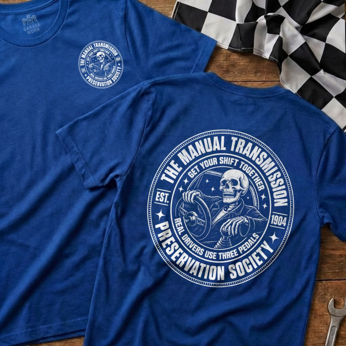 Blue t-shirt with skull driving graphic and "Manual Transmission Preservation Society" text.