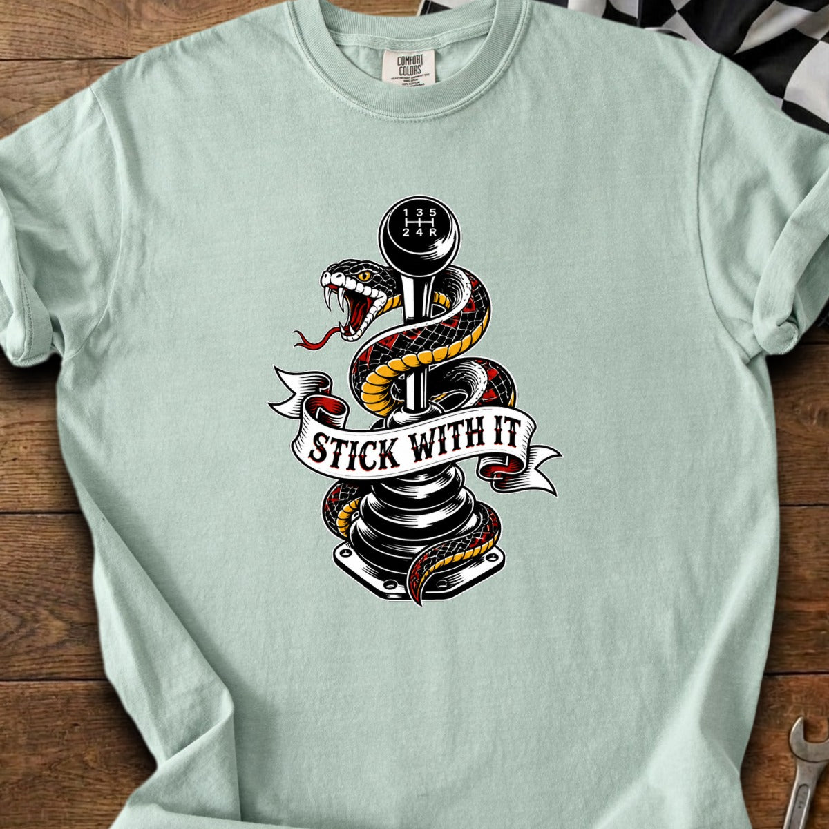 Snake wrapped around a manual transmission shifter with "STICK WITH IT" banner.