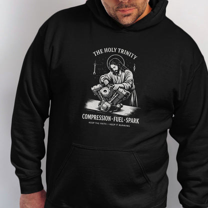 Black hoodie with Jesus working on a motorcycle engine, text "The Holy Trinity".