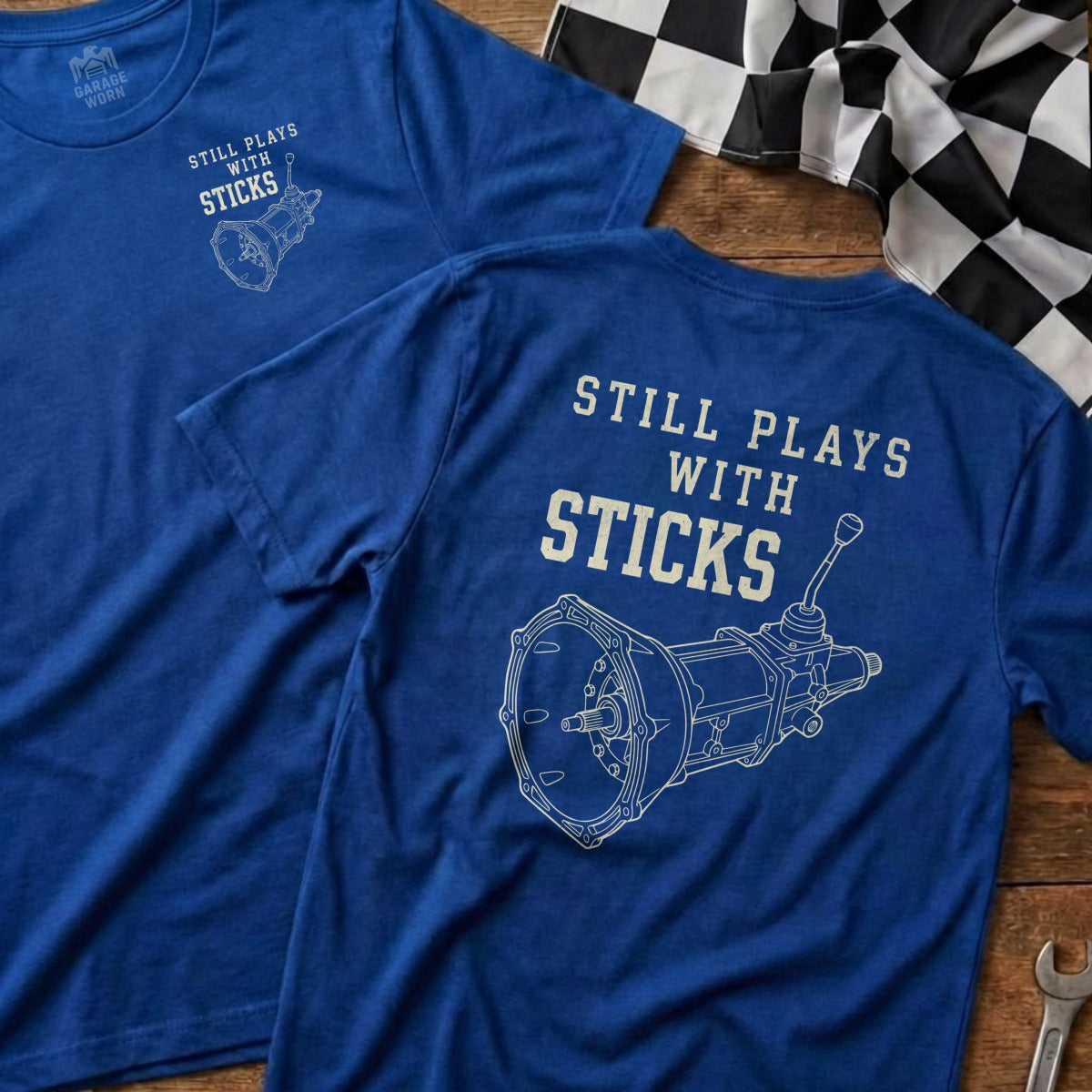 Blue t-shirt with "Still plays with sticks" and manual transmission graphic.