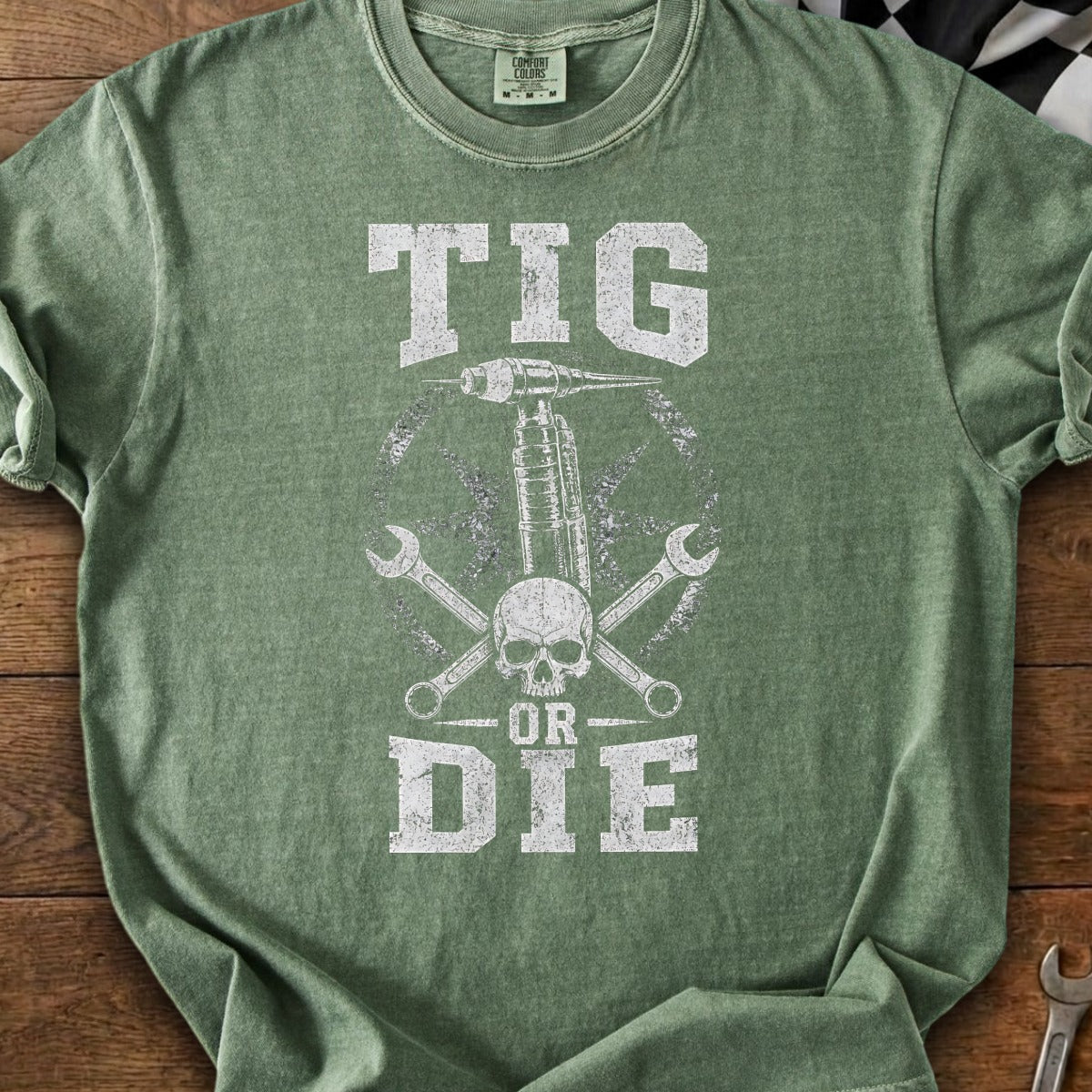Green t-shirt with "TIG OR DIE" graphic featuring a skull, welder, and wrenches.