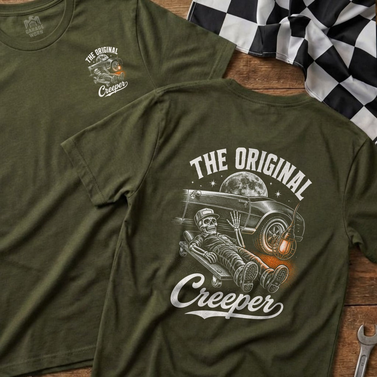 Green t-shirt with skeleton mechanic on creeper under classic car.