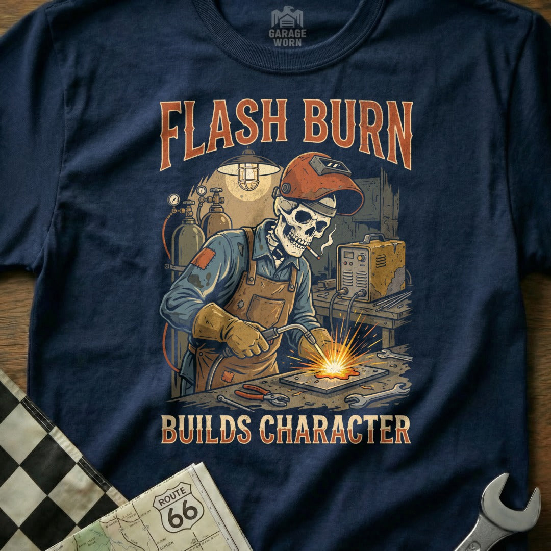 Skeleton welder with "Flash Burn Builds Character" text on a navy t-shirt.