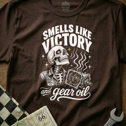 Brown t-shirt with skeleton holding gearbox, reads "Smells Like Victory and Gear Oil".