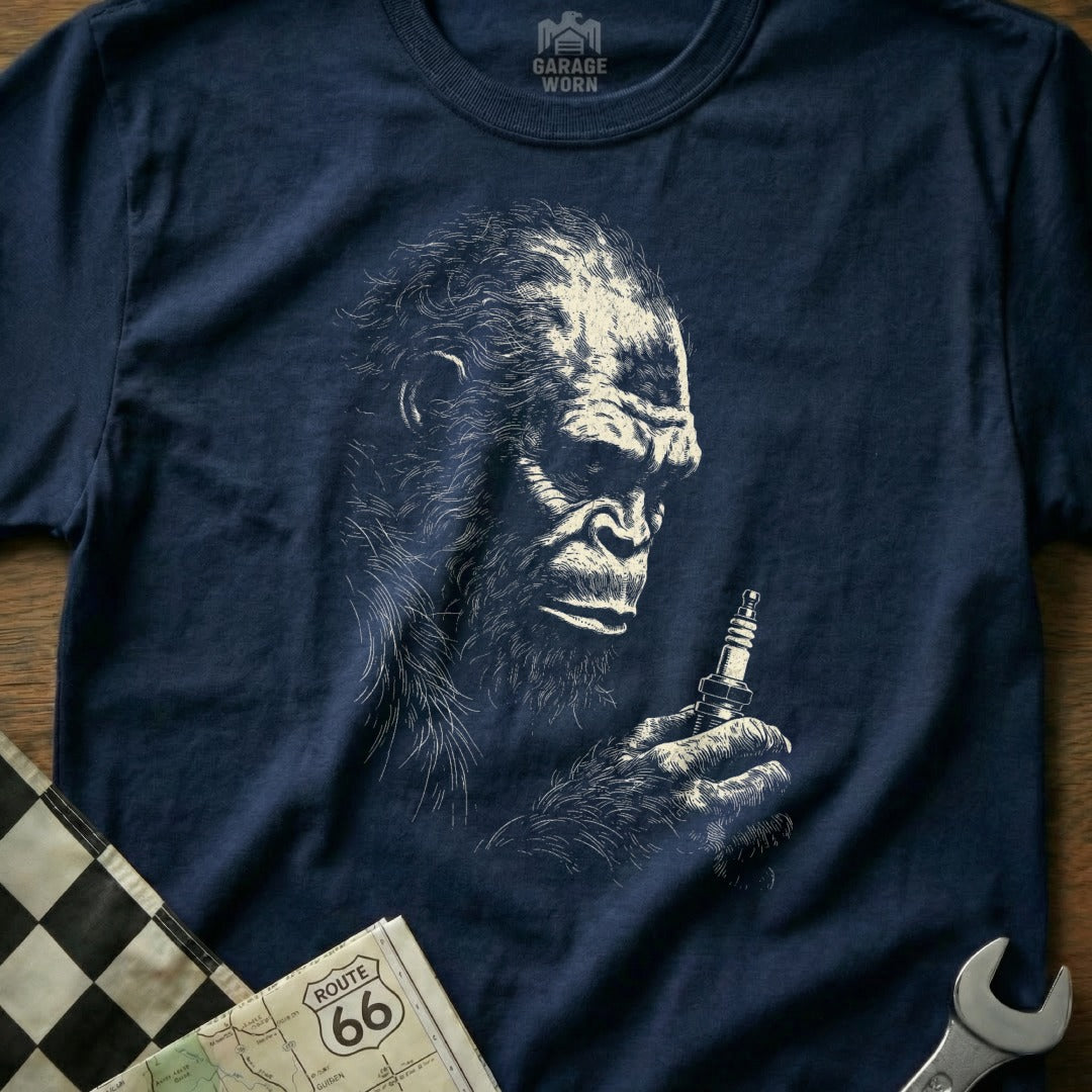 Navy t-shirt with a sketch of Bigfoot holding a spark plug.