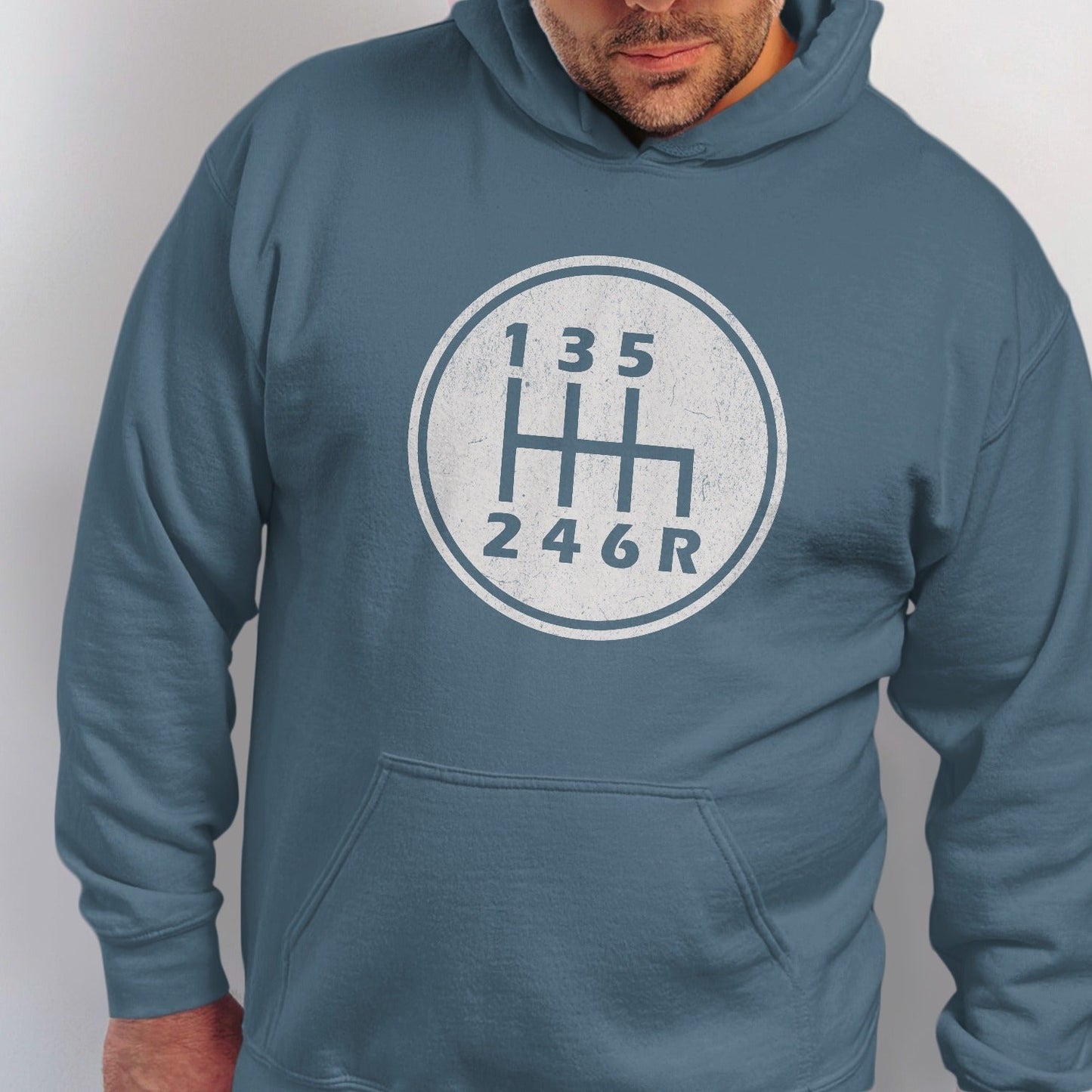 Man wearing blue hoodie with white manual transmission shift pattern graphic.