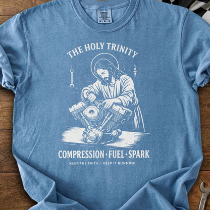 Blue t-shirt with Jesus working on a motorcycle engine, "The Holy Trinity" and "Compression Fuel Spark" text.