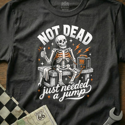 Skeleton with jumper cables connected to a charger, text reads "Not Dead just needed a jump".