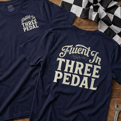 Navy t-shirt with "Fluent In THREE PEDAL" printed on the back.