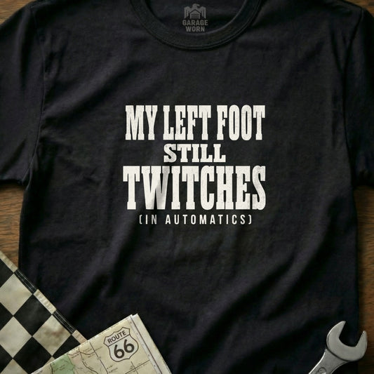 Black t-shirt with white text "My left foot still twitches (in automatics)".