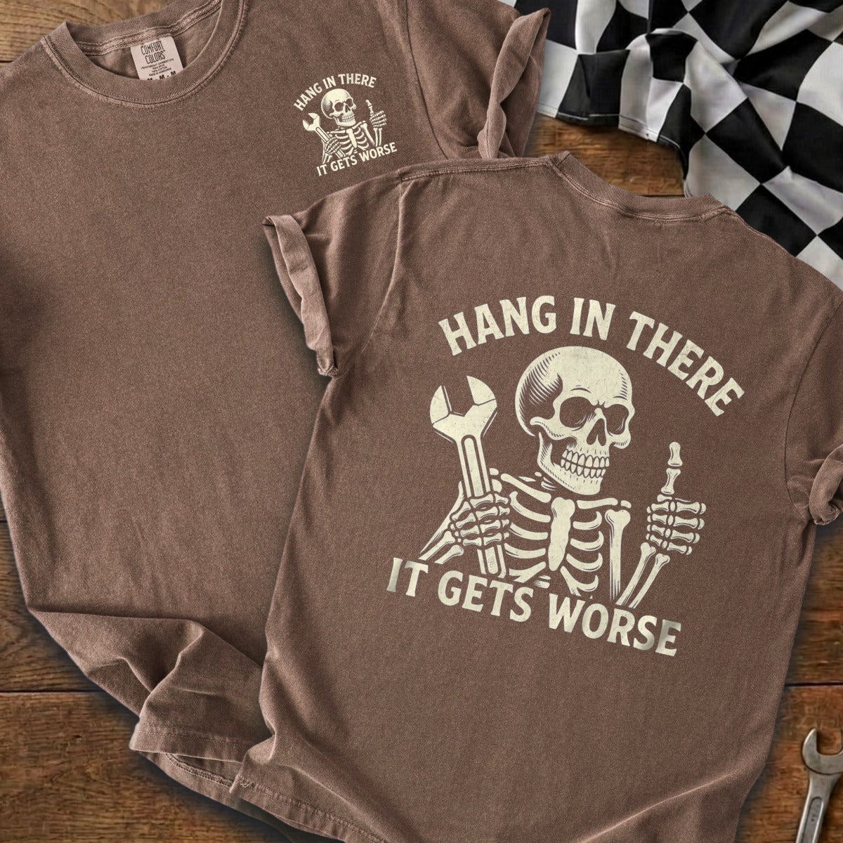 Brown t-shirt with skeleton graphic holding wrench and giving thumbs up.