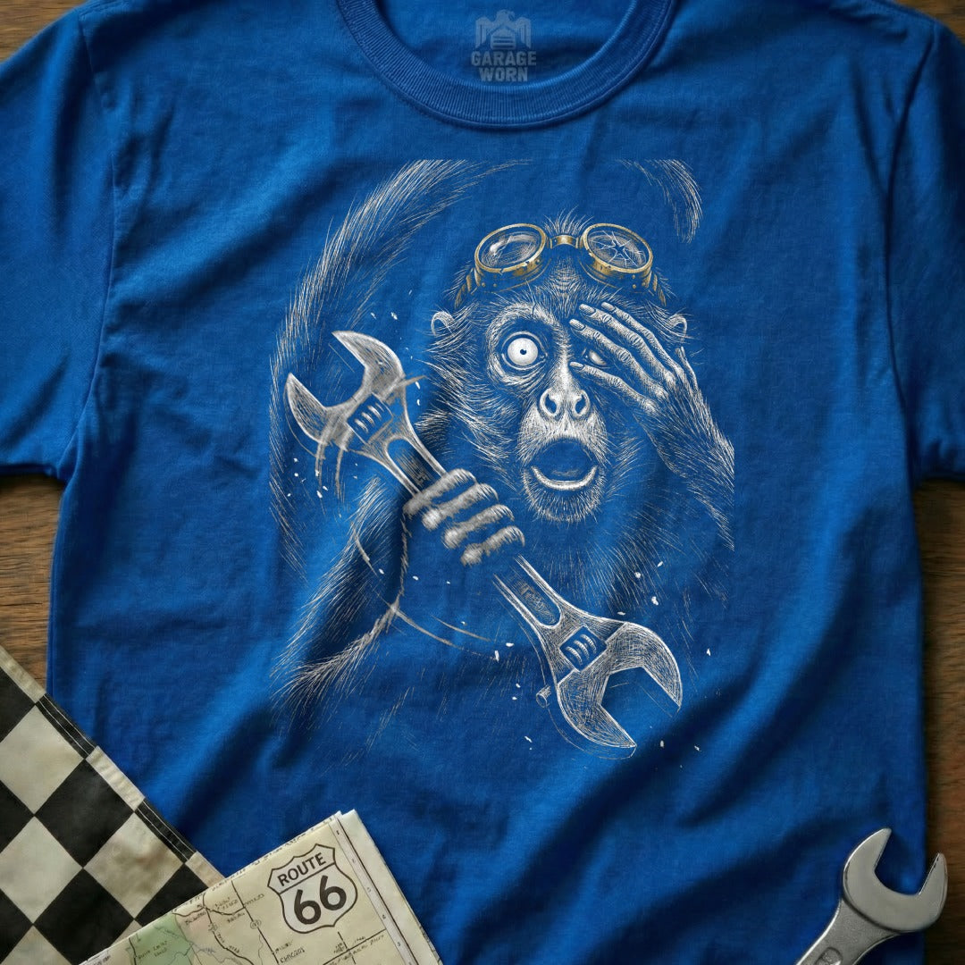 Monkey in goggles holding wrenches, distressed drawing on blue t-shirt.
