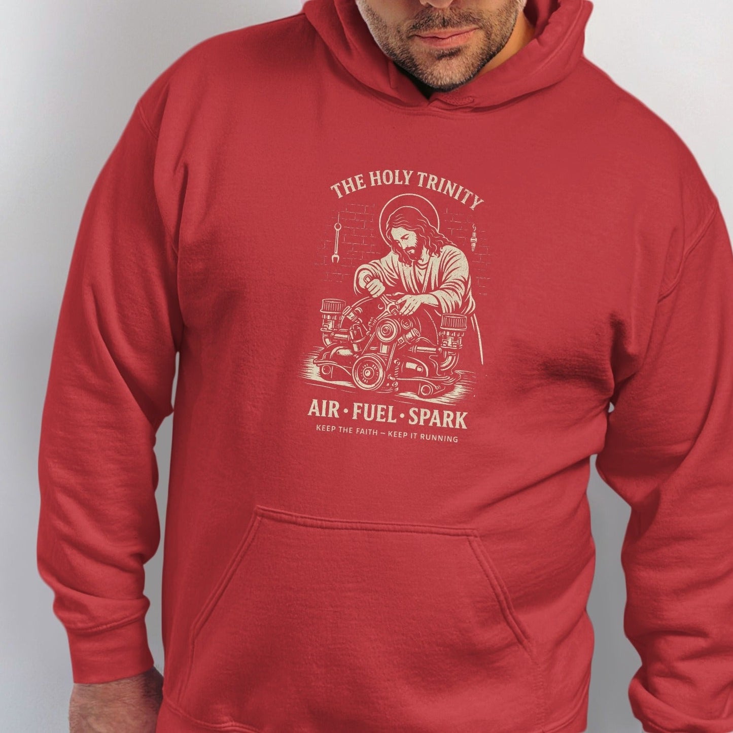 Red hoodie with graphic of Jesus working on an engine, "THE HOLY TRINITY" and "AIR FUEL SPARK".