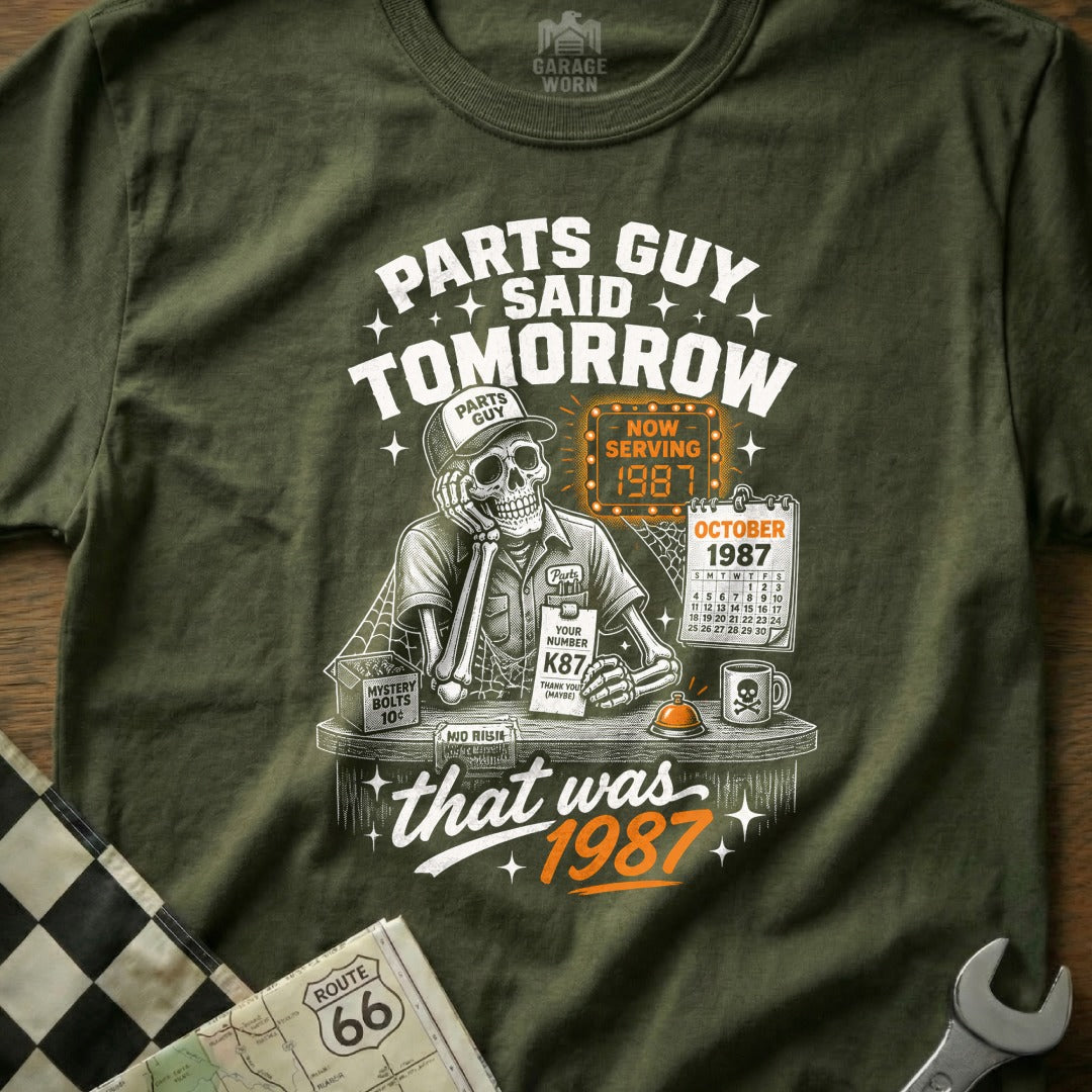 Skeleton mechanic in a cap and uniform saying "Parts Guy Said Tomorrow" with "Now Serving 1987".
