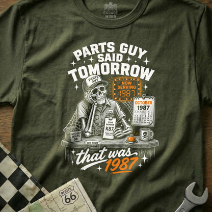 Skeleton mechanic in a cap and uniform saying "Parts Guy Said Tomorrow" with "Now Serving 1987".