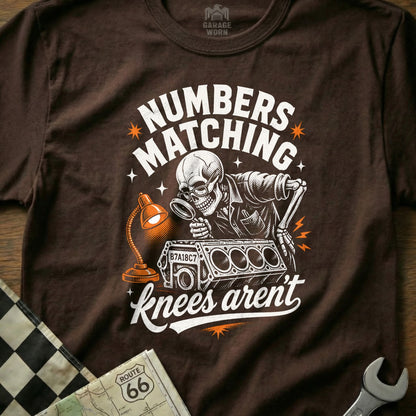 Brown t-shirt with skeleton mechanic examining engine with "Numbers Matching" text.