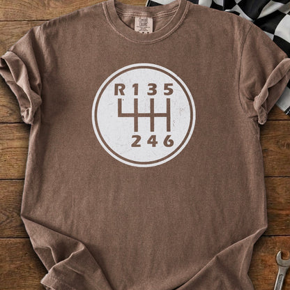 Brown t-shirt with a white manual transmission gear shift pattern graphic.